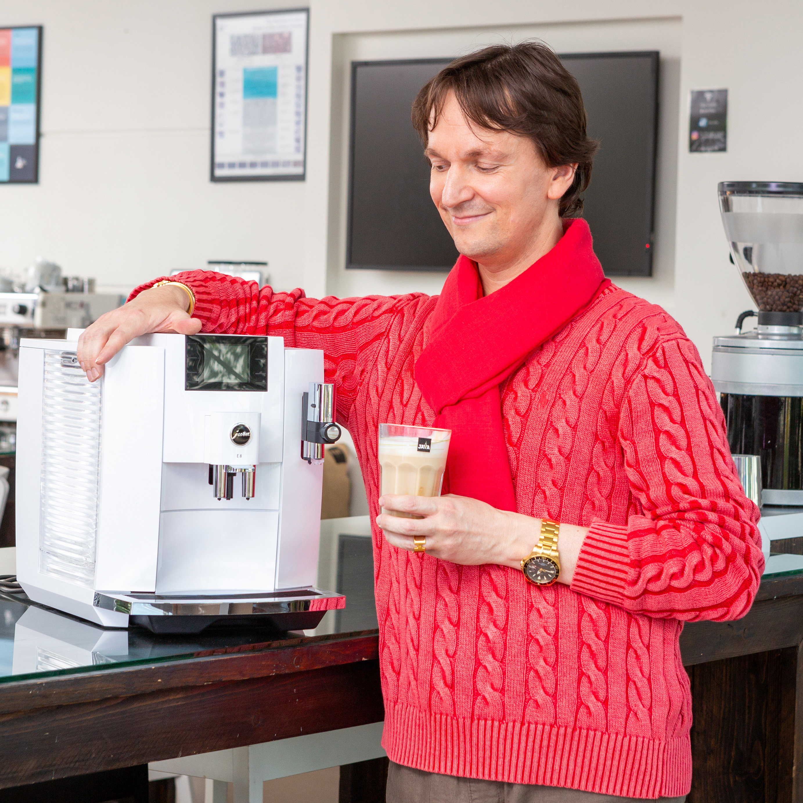 Medewerker met koffietoestel naast zich en koffie in de hand