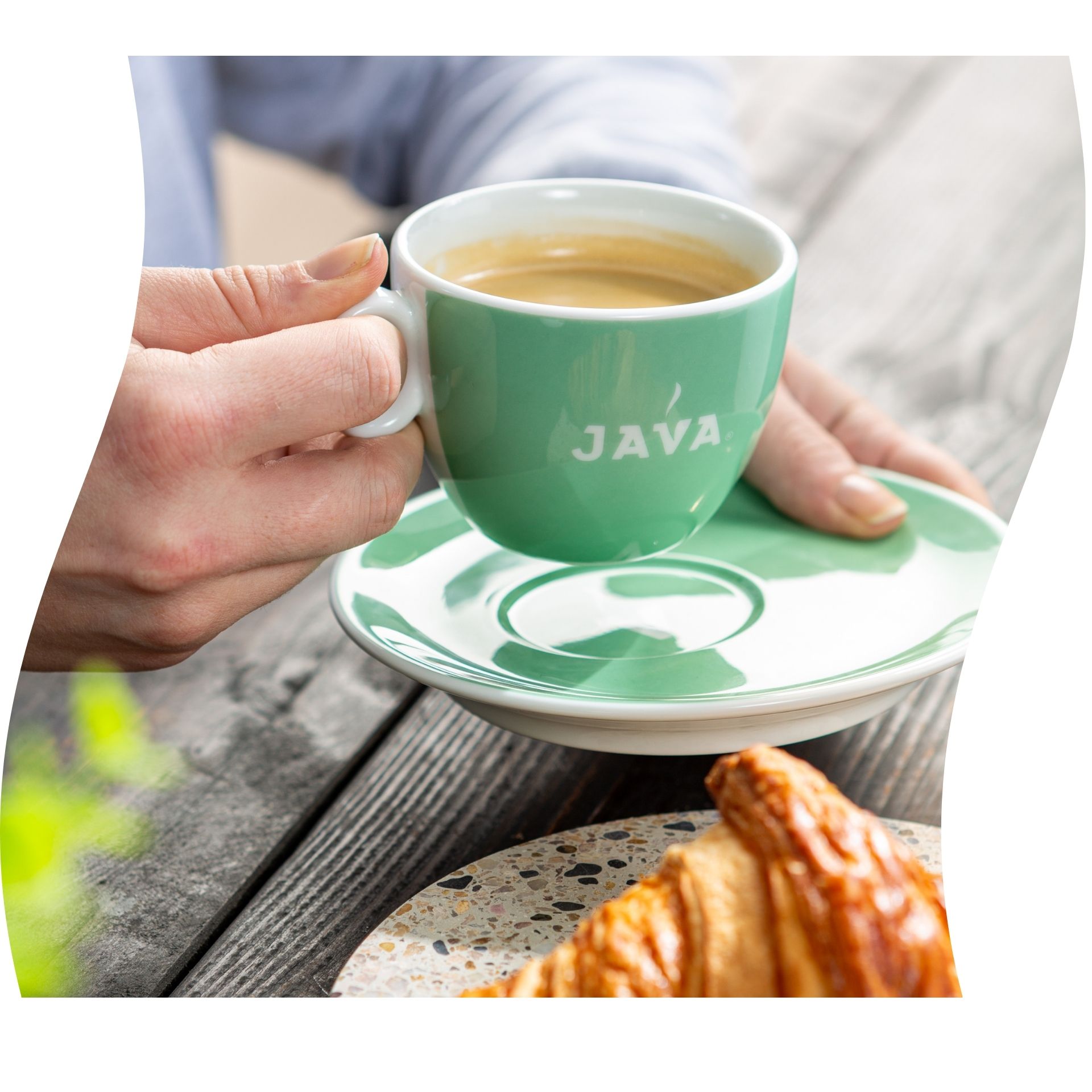 Koffie in groen porseleinen kopje met onderbordje en croissant